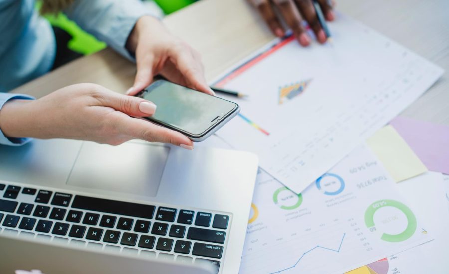 Fotografía de persona revisando informes de analytics en smartphone y portátil representando el servicio de gestión de redes sociales de Adrián García